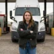 Female truck driver standing confidently in front of semi-truck at Ohio truck stop unbothered by AI replacement concerns
