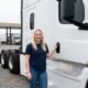 Female owner-operator standing beside bobtail semi-truck tractor without trailer at Columbus Ohio truck stop